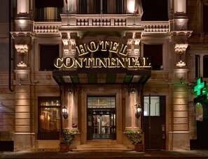 Exterior del Hotel Continental con una entrada imponente, columnas ornamentales y una fachada bien iluminada.