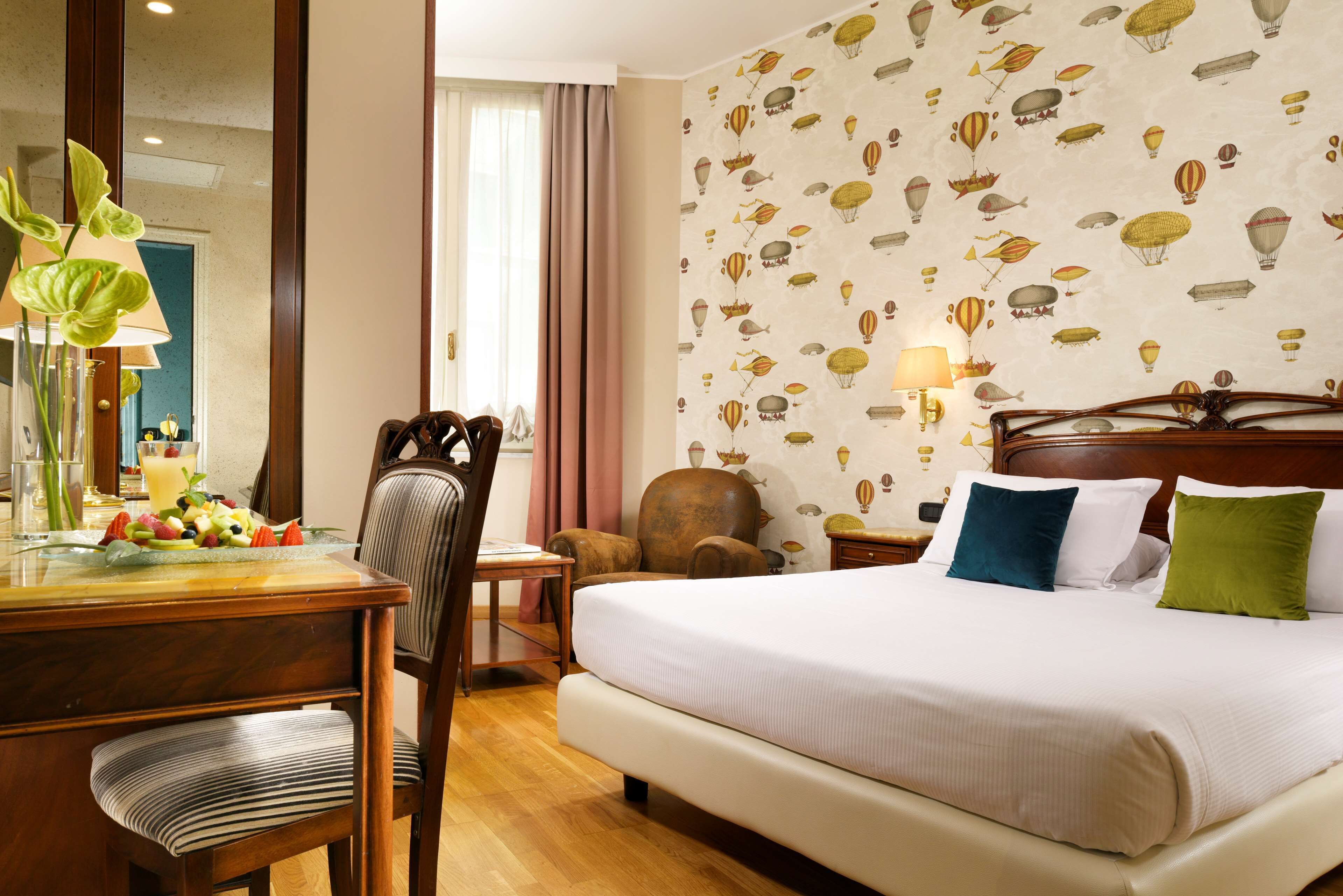 Una camera d'albergo con un letto grande, una scrivania in legno, una sedia e una parete decorata con un motivo a dirigibile.