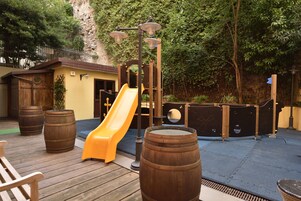 Un molo in legno con uno scivolo, botti di legno e un piccolo edificio con una porta.
