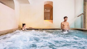 A hot tub with two people, one standing and one sitting, surrounded by water.