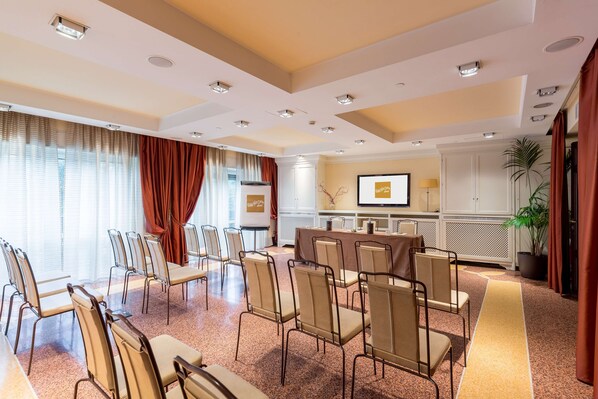 A conference room with a long table, chairs, and a large window with curtains.