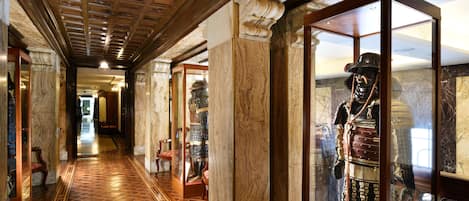 A hallway with marble columns, a patterned floor, and a display case with historical artifacts.