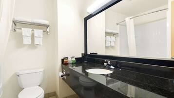 Un bagno con un water bianco, un lavandino nero e uno specchio grande.