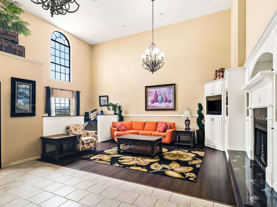 A spacious living room with a large window, a chandelier, and a fireplace.