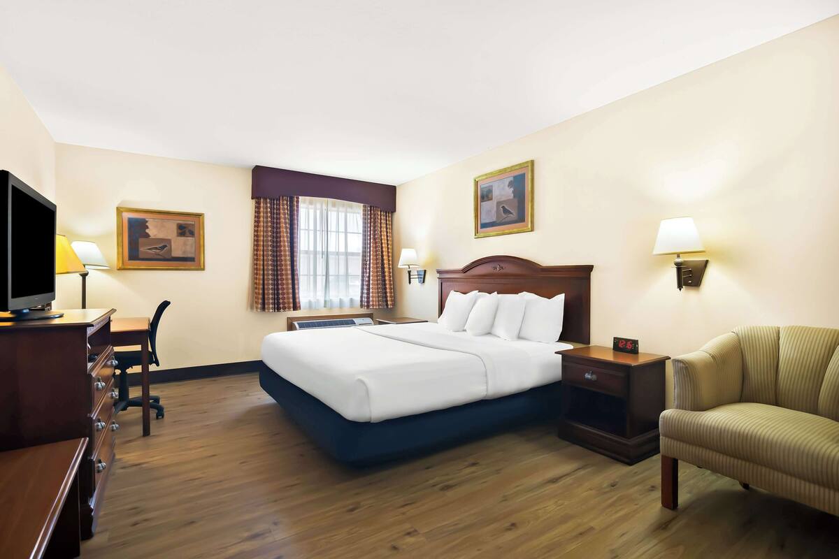 Een hotelkamer met een bed, bureau, stoel en een televisie.