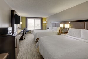 A hotel room with two beds, a desk with a computer, a TV, and a window with a view.