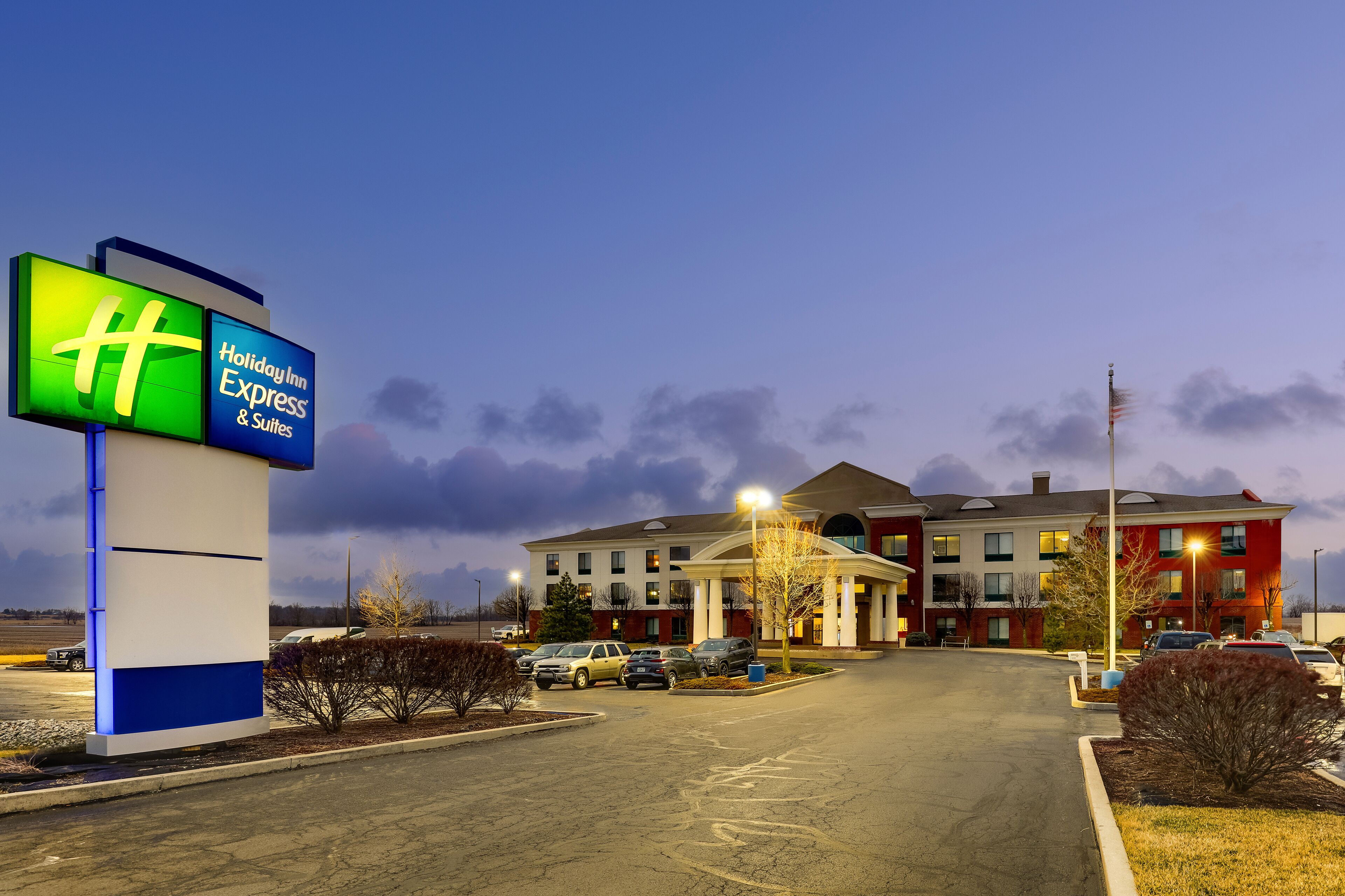 A Holiday Inn Express & Suites hotel with a parking lot and a building with multiple windows and a red facade.