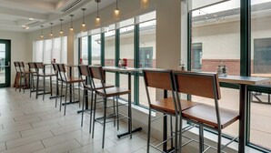 A modern indoor dining area with metal chairs and tables, large windows, and pendant lighting. - Holiday Inn Express & Suites Montpelier by IHG (Montpelier)