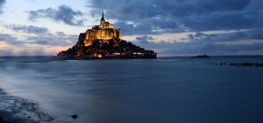 A historic castle on a rocky island with a calm sea in the foreground. - Hôtel de la Digue (Le Mont-Saint-Michel)