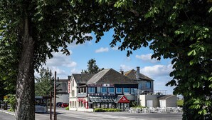 A building with a restaurant and bar on the ground floor, a hotel sign, and a view of Mont Saint Michel. - Hôtel de la Digue (Le Mont-Saint-Michel)