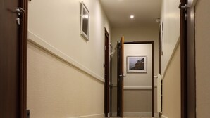 A hallway with a tiled floor, wooden doors, and a framed picture on the wall. - Hôtel de la Digue (Le Mont-Saint-Michel)