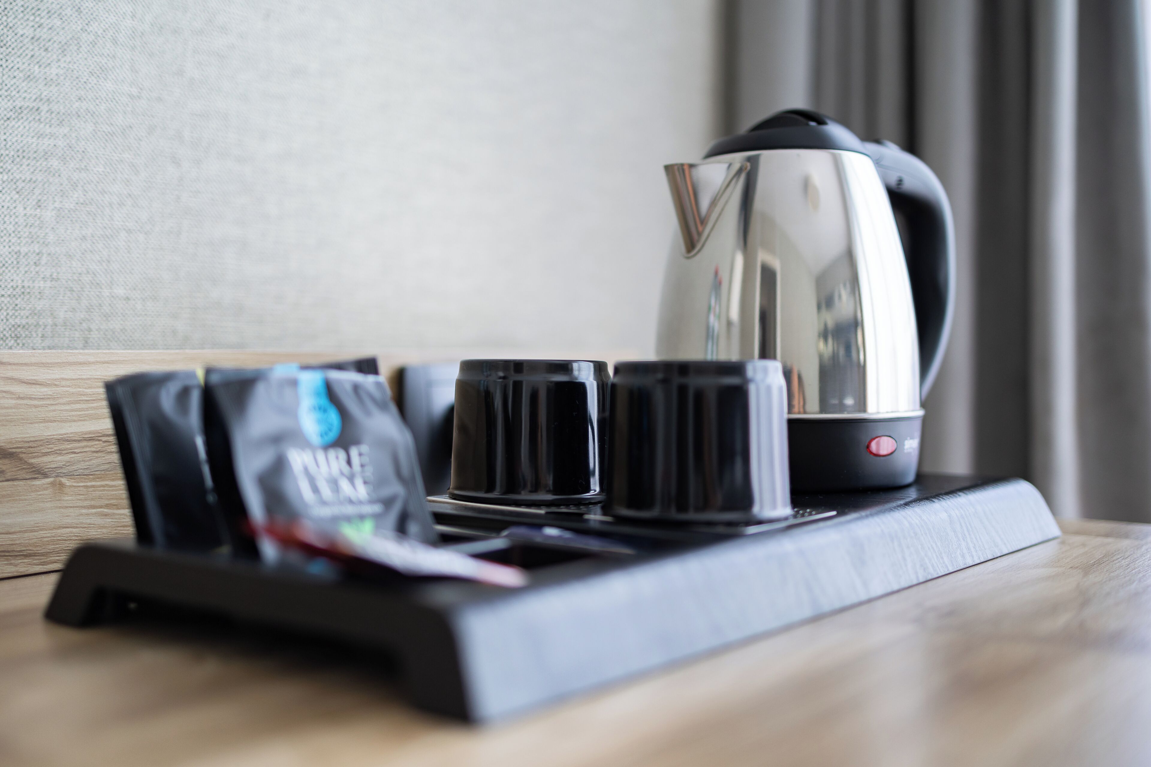 Una cafetera, cuatro tazas y una bolsa de café sobre una bandeja.