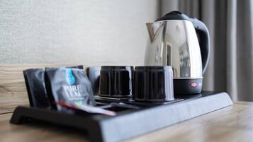Una cafetera, cuatro tazas y una bolsa de café sobre una bandeja.