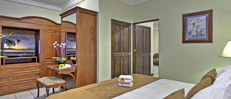 Une chambre d’hôtel avec un lit, un bureau et une chaise, une armoire et un tableau au mur.