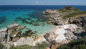 Une plage rocheuse avec une eau turquoise cristalline et une vue sur la mer.