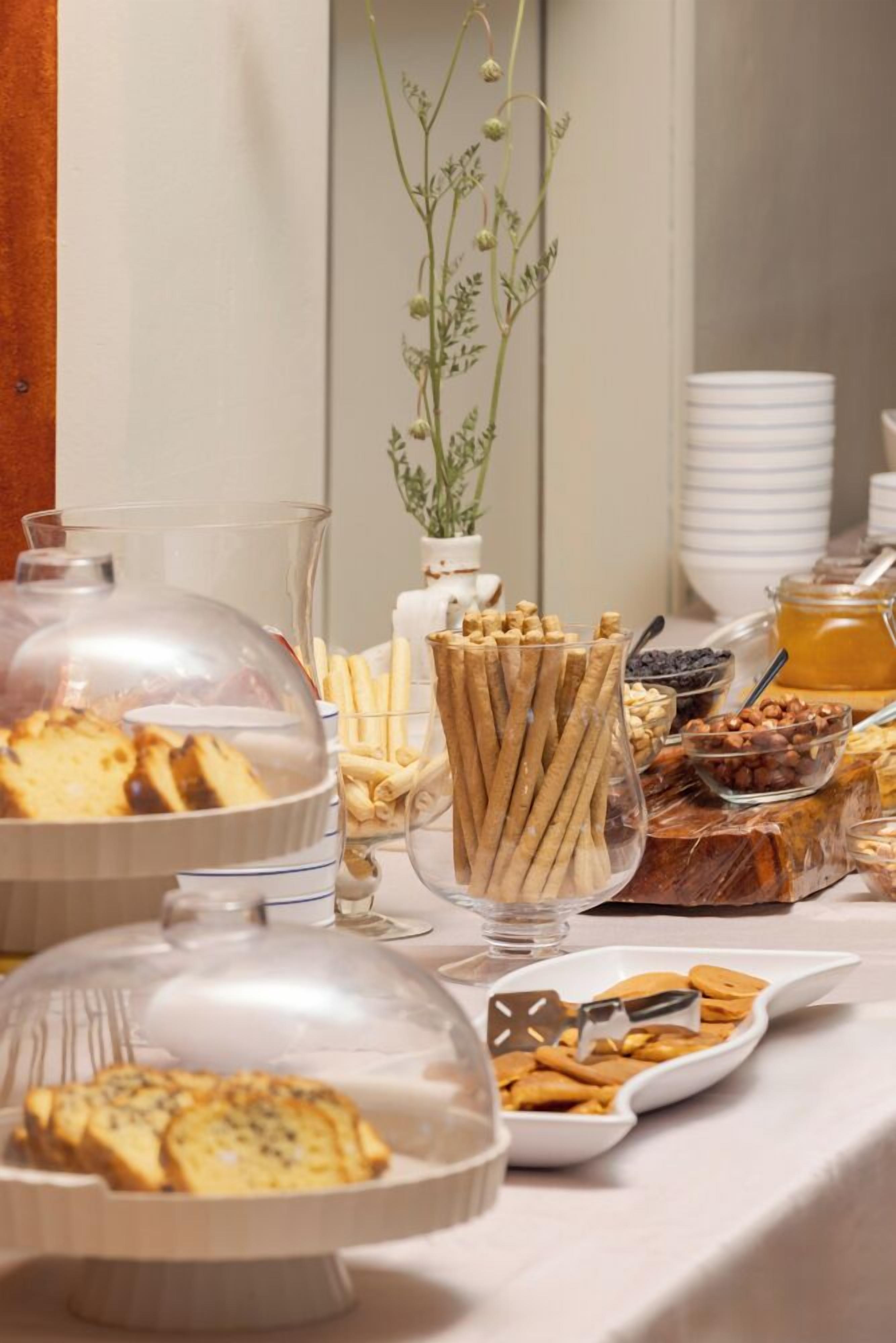 A buffet table with various food items, including bread, pastries, and a honey jar.