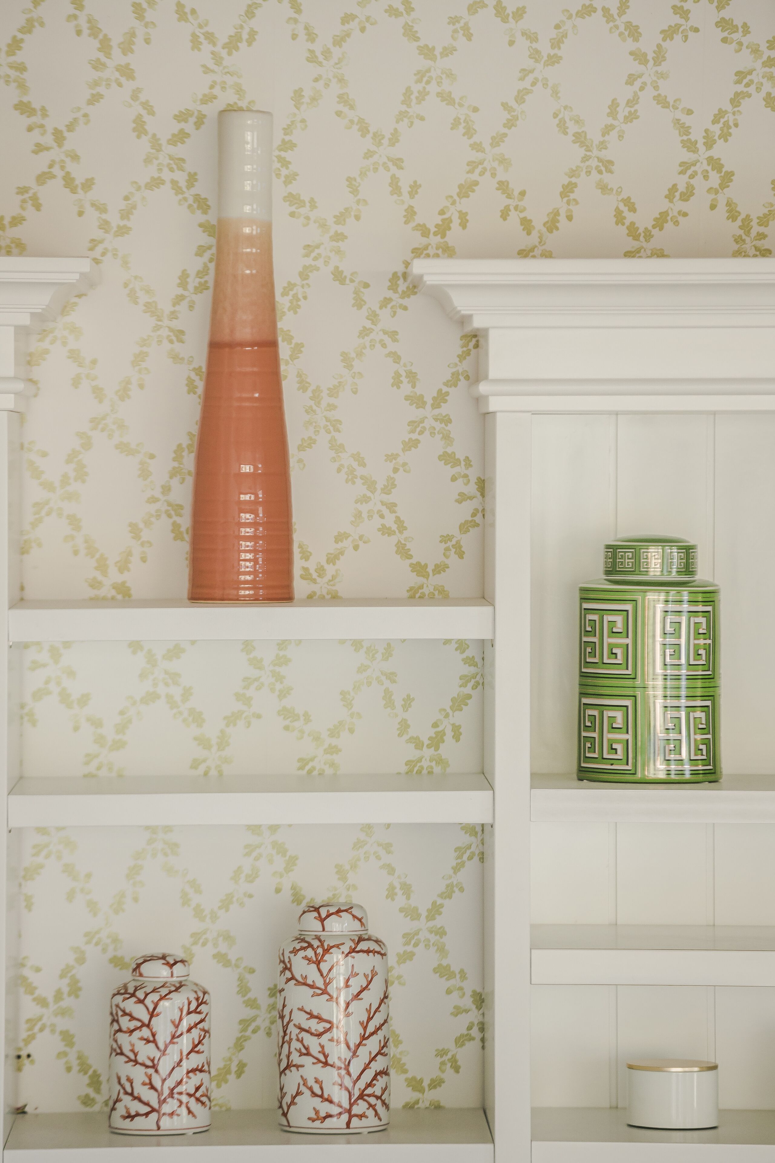 Uno scaffale con vasi decorativi e un contenitore in ceramica verde.