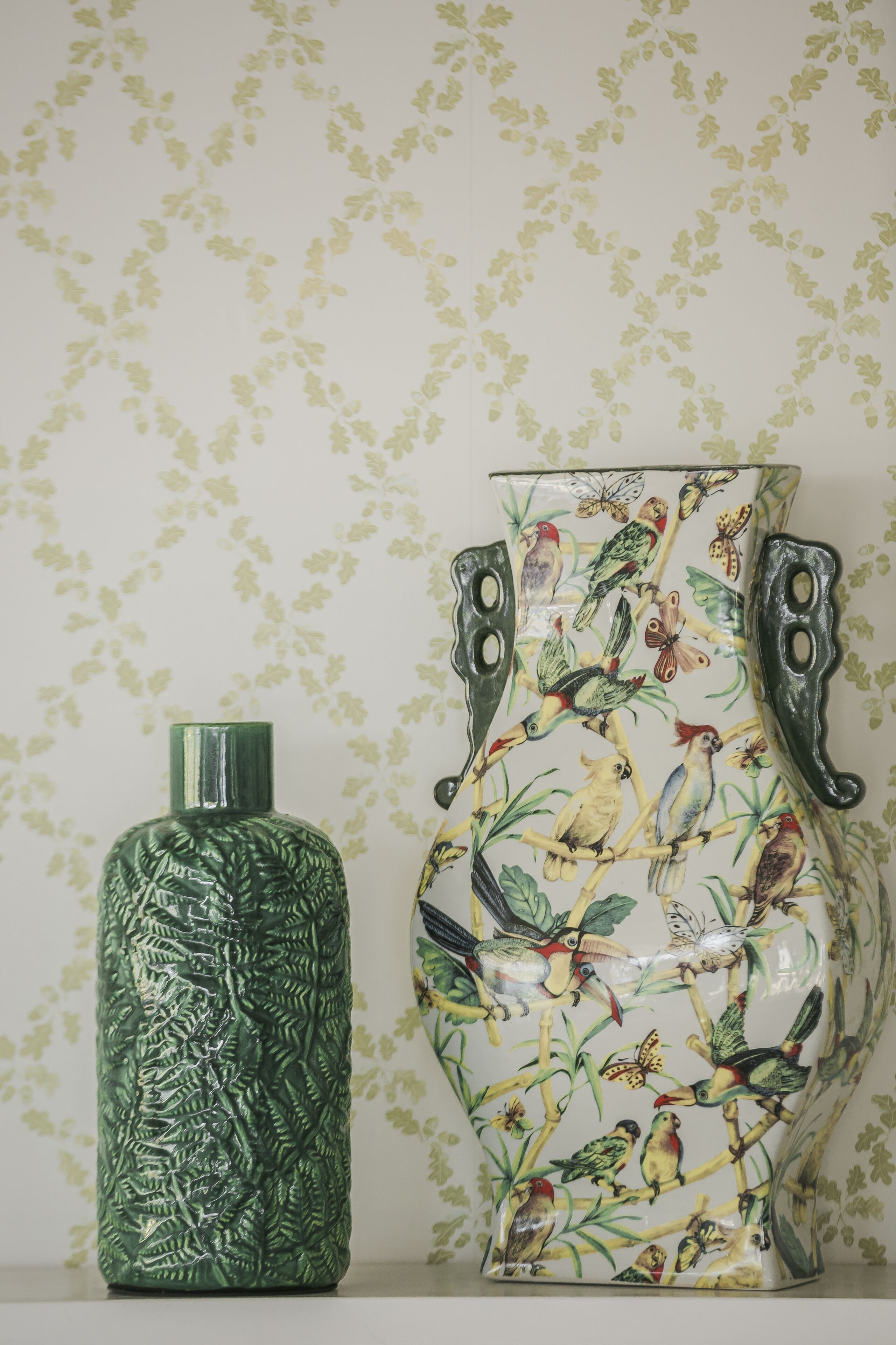 Un vase vert orné d’un motif texturé et un vase plus grand décoré d’oiseaux et de papillons.