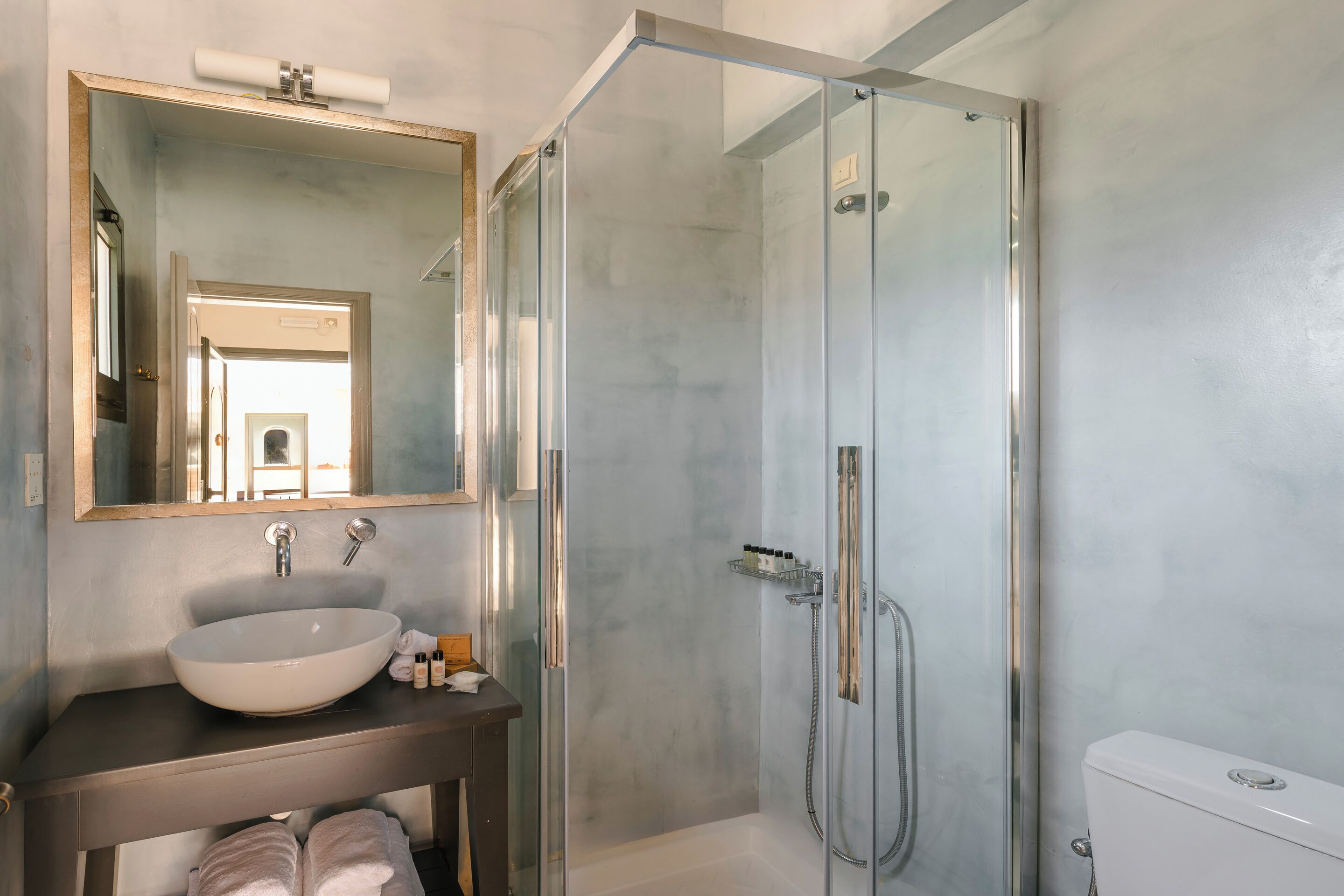 Ein modernes Badezimmer mit einer Glasdusche, einem großen Spiegel und einem weißen Waschbecken.