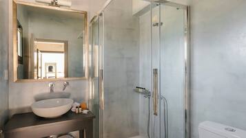 Ein modernes Badezimmer mit einer Glasdusche, einem großen Spiegel und einem weißen Waschbecken.