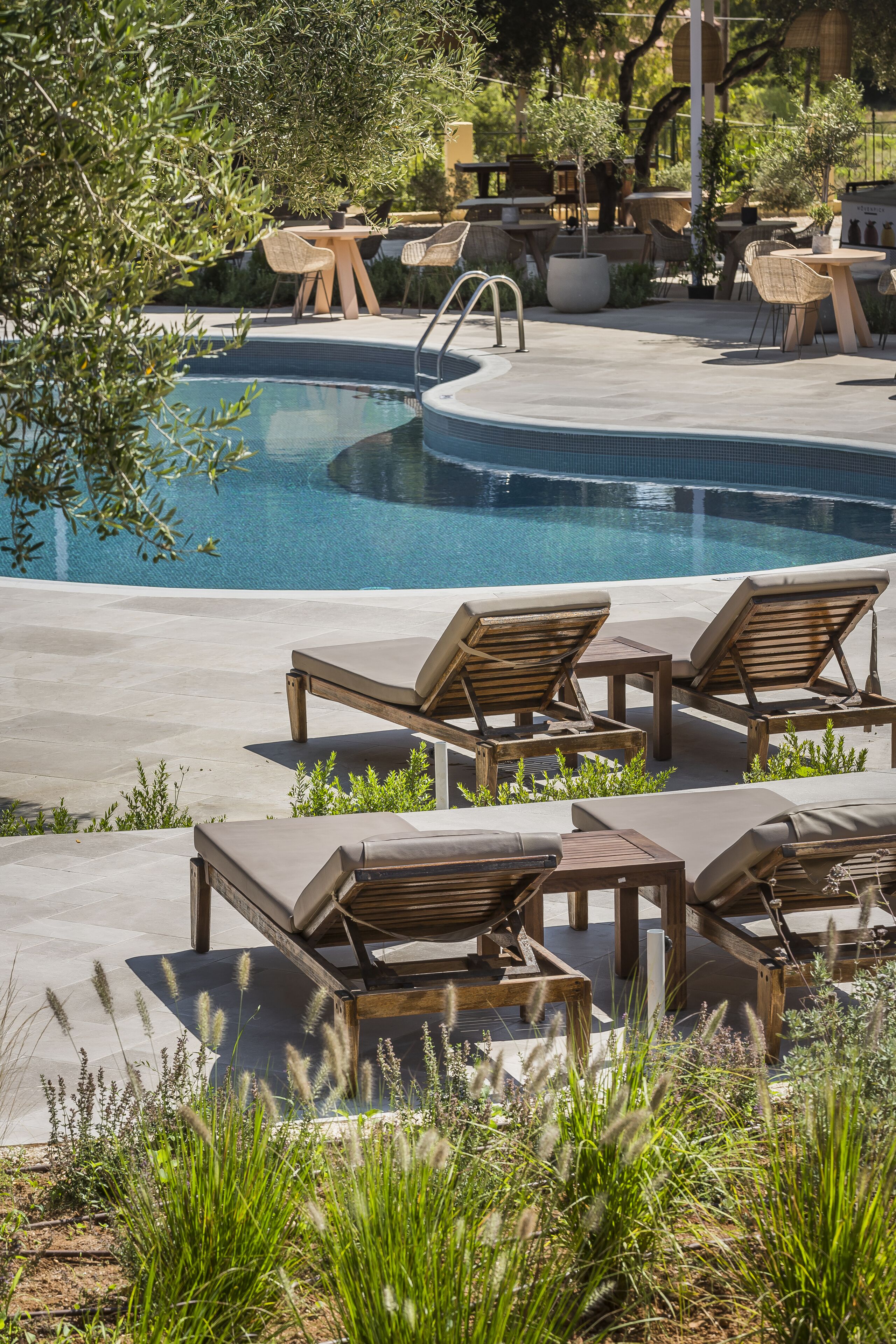 A pool area with lounge chairs, a small table, and a seating area with chairs and a table.