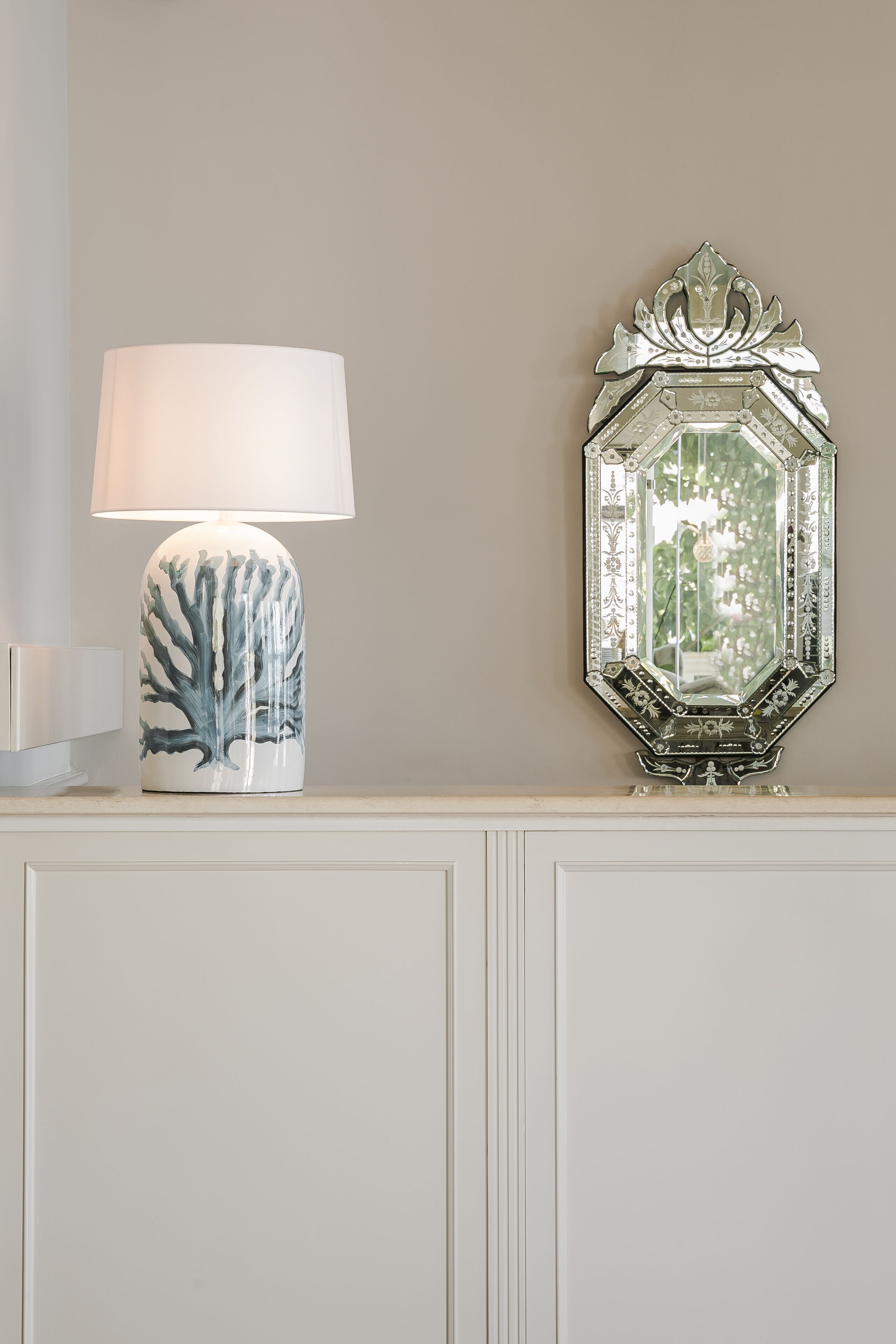 A table lamp with a leaf design and a decorative mirror with a geometric frame.