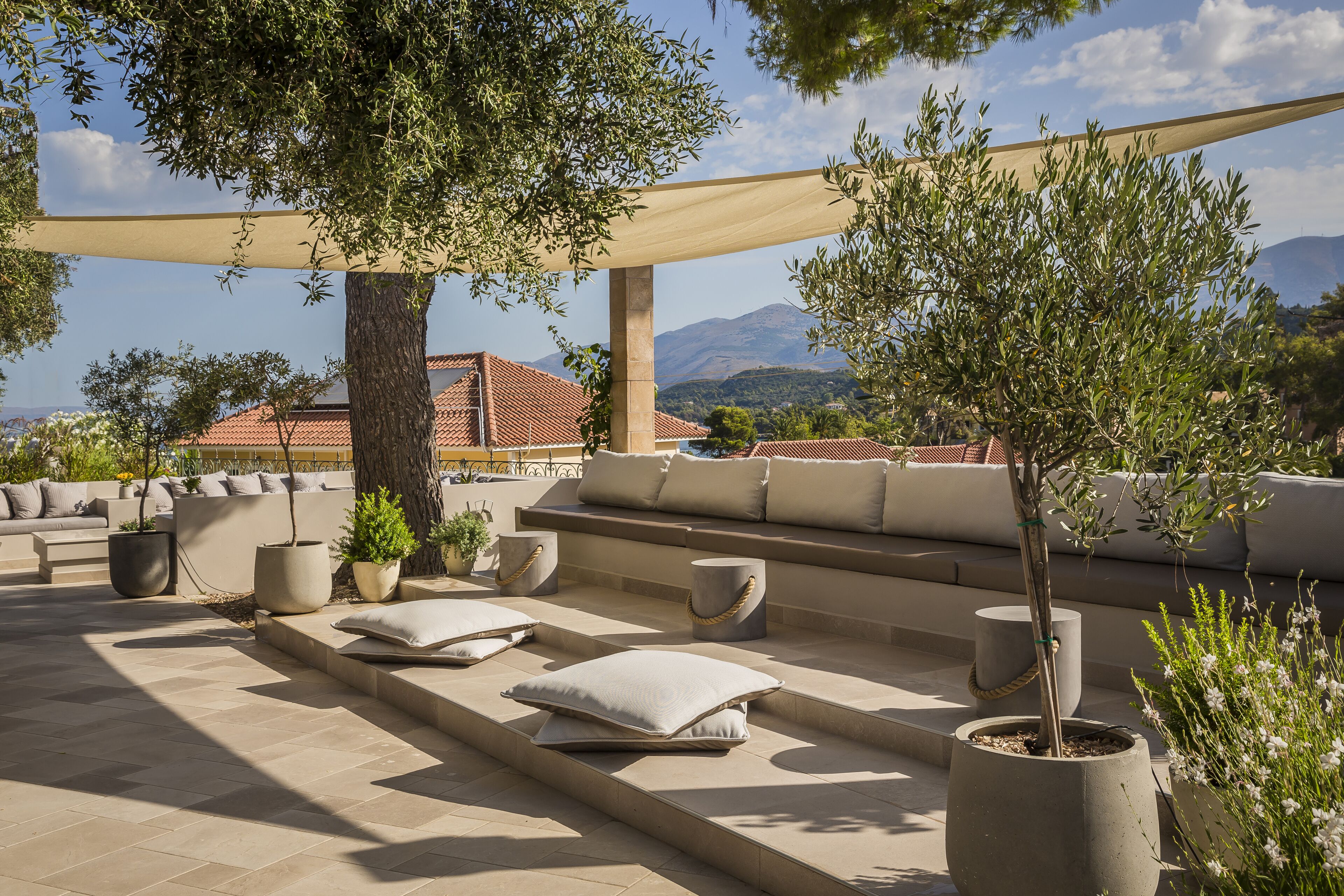 An outdoor seating area with a sofa, cushions, and potted plants.