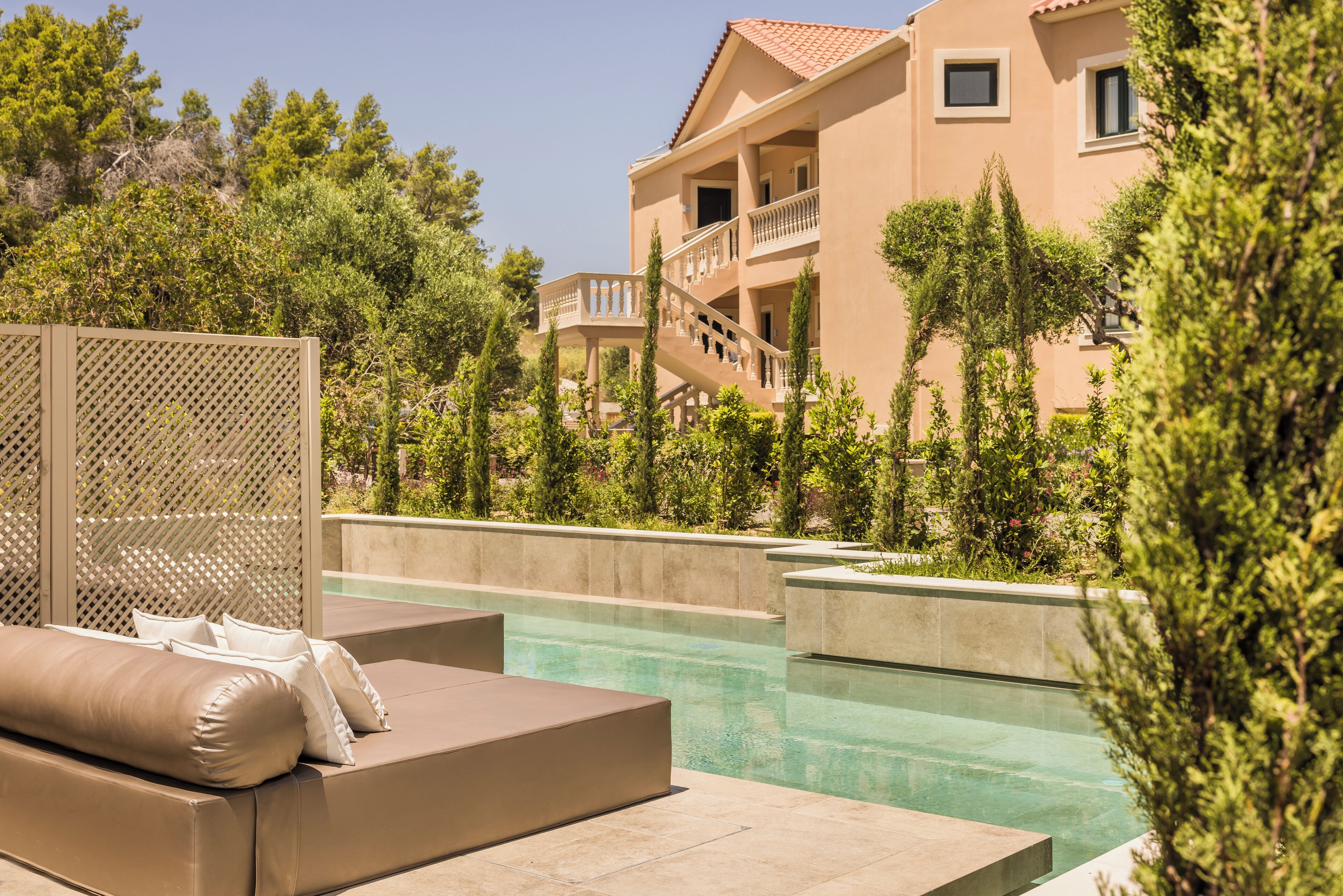 A pool area with lounge chairs and a building with balconies.