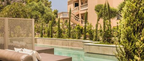 A pool area with lounge chairs and a building with balconies.
