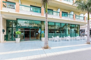 A hotel with a modern facade, large glass windows, and outdoor seating area. - Hotel Torremar – Mares (Velez-Malaga)
