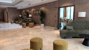 Un hall d’entrée spacieux, doté d’un grand canapé, de quelques fauteuils, d’une plante en pot et d’un design moderne.