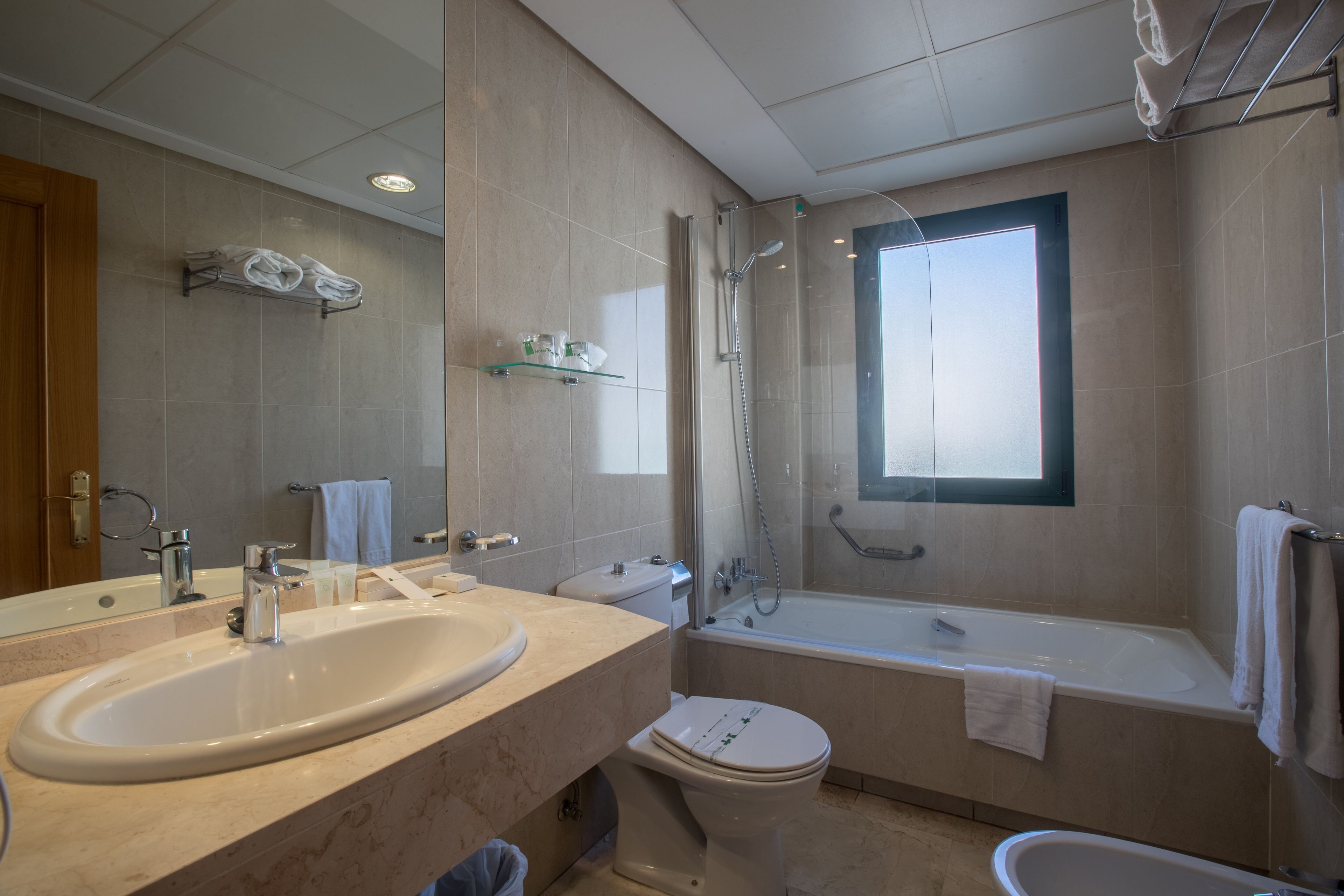 A modern bathroom with a large sink, toilet, bathtub, and shower.