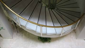 Una escalera de caracol con barandilla blanca y una planta verde en la base.