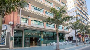 Un hôtel doté d’une façade moderne, de nombreux balcons et d’un espace extérieur aménagé pour s’asseoir.