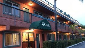 A hotel with a green awning, a visible office entrance, and a balcony with railings.