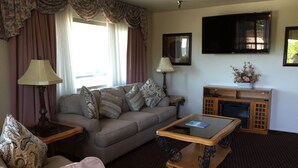 A living room with a sofa, two lamps, a flat-screen TV, and a small cabinet.