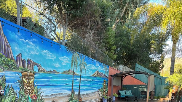 A poolside area with lounge chairs, a mural depicting a tropical beach scene, and a small pool.