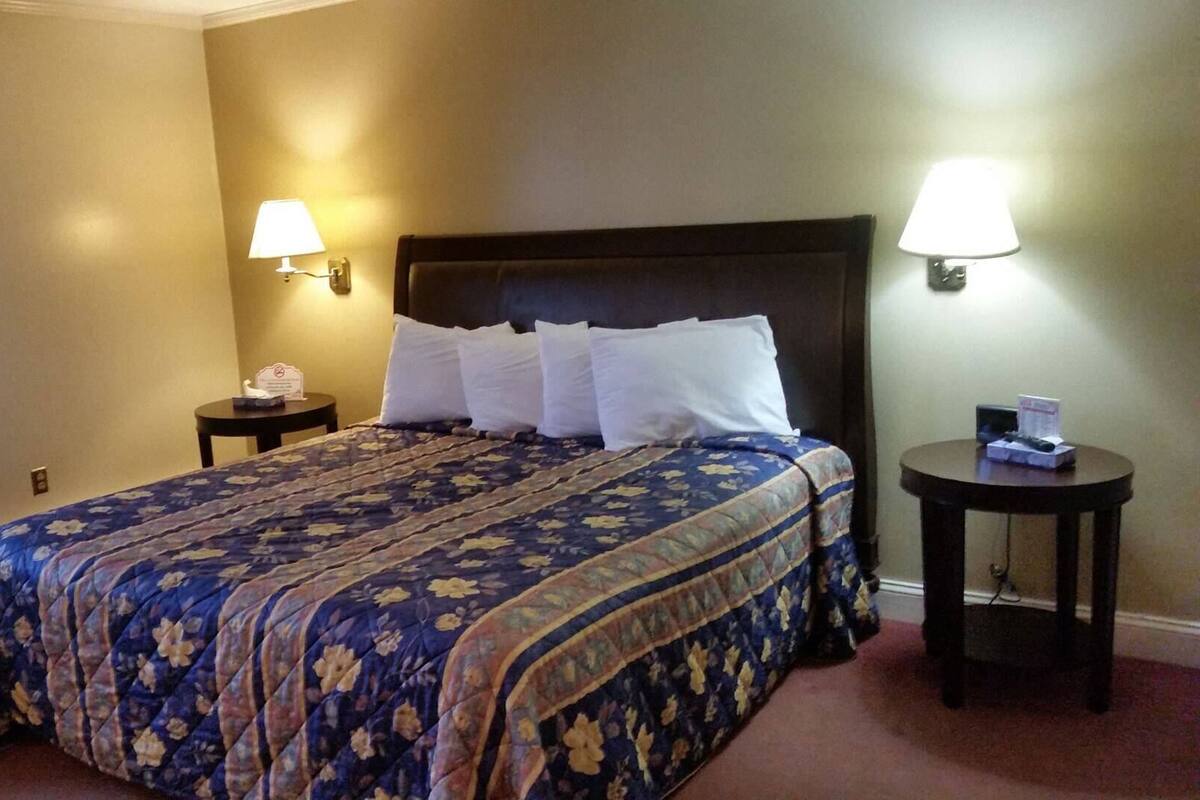 A hotel room with a large bed, two bedside tables, and two wall-mounted lamps.