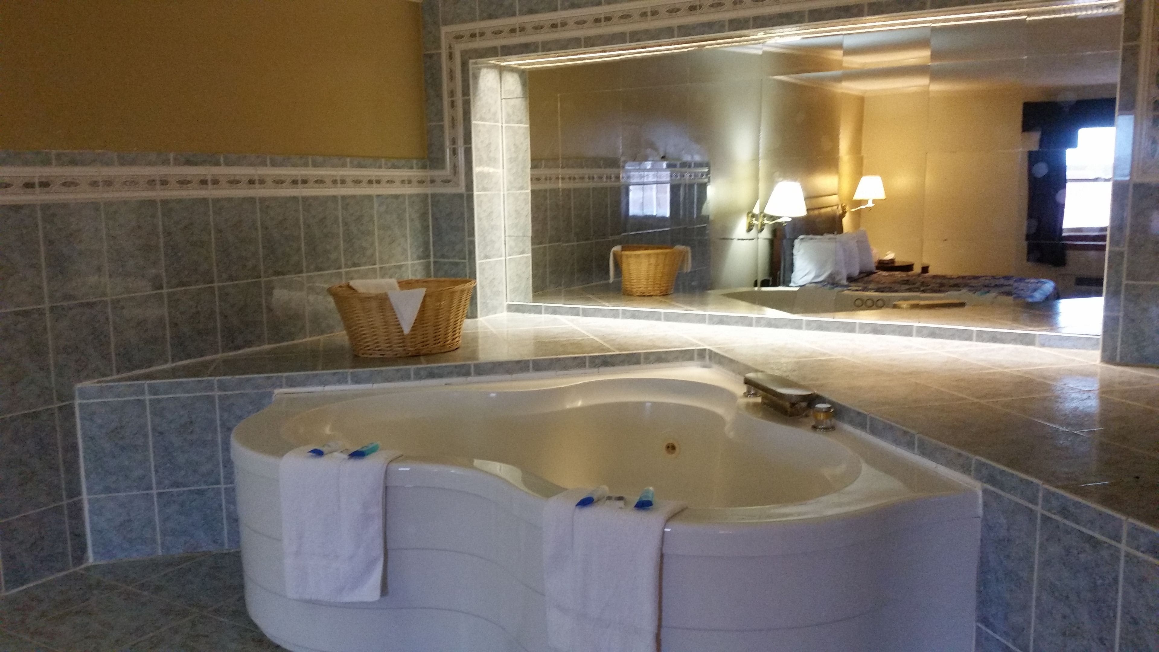 Une salle de bain avec une grande baignoire, un miroir et un panier en osier posé sur le comptoir.