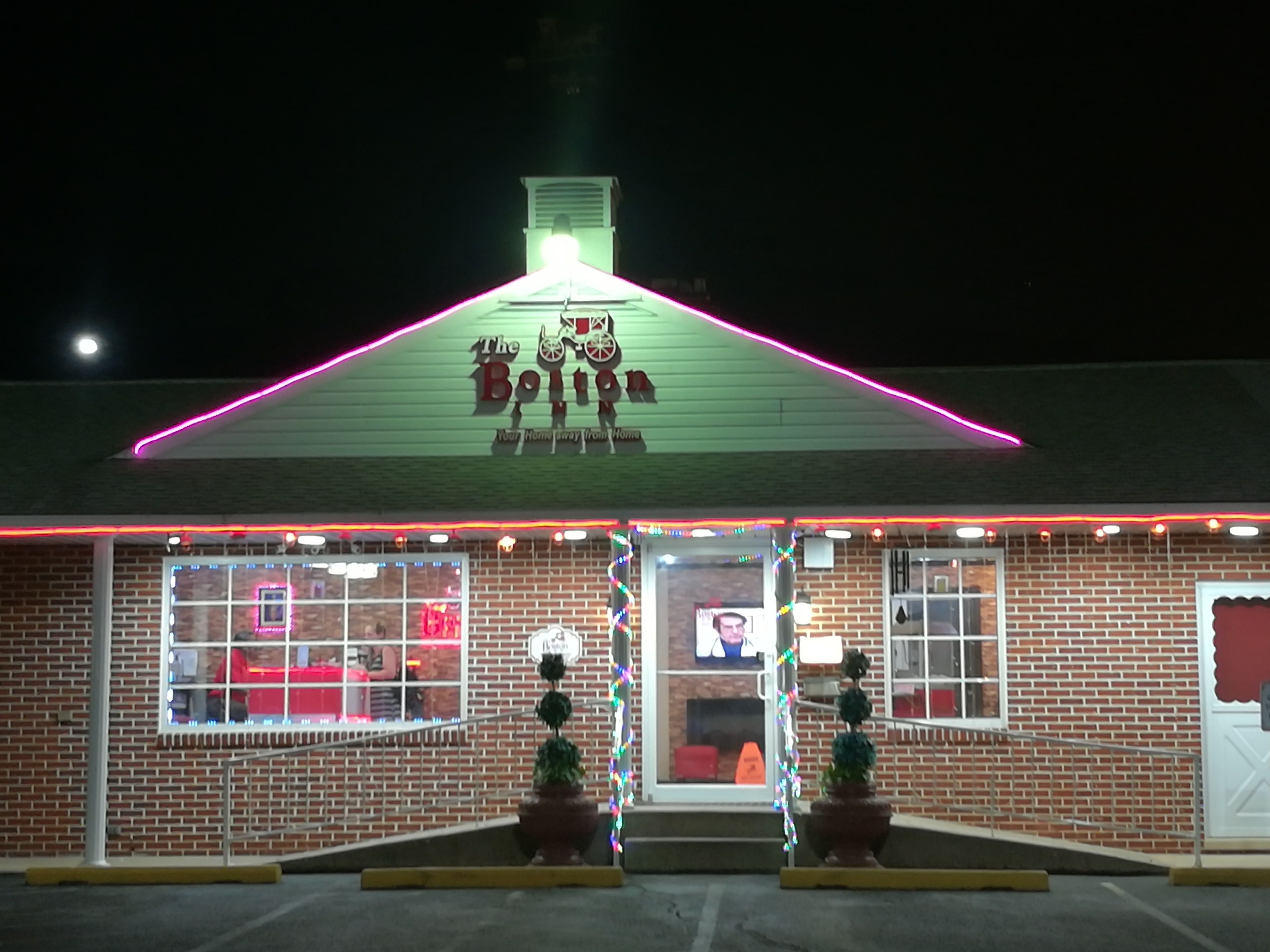 A brick building with a green roof and neon lights.