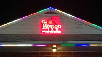 A building with a neon sign for 'The Boston Inn' and colorful LED lights along the roofline.