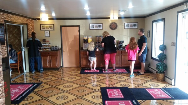 A hotel lobby with a reception desk, a coffee machine, and a clock on the wall. - Boston Inn (Westminster)