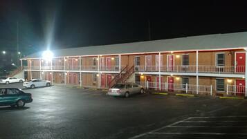 A motel with a two-story structure, multiple rooms, and a parking lot with several cars.