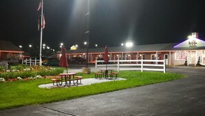 A well-lit outdoor area with a white fence, picnic tables, and a flagpole.