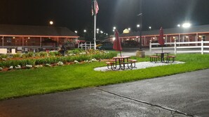 A well-lit outdoor area with a flagpole, tables, and chairs arranged for dining.