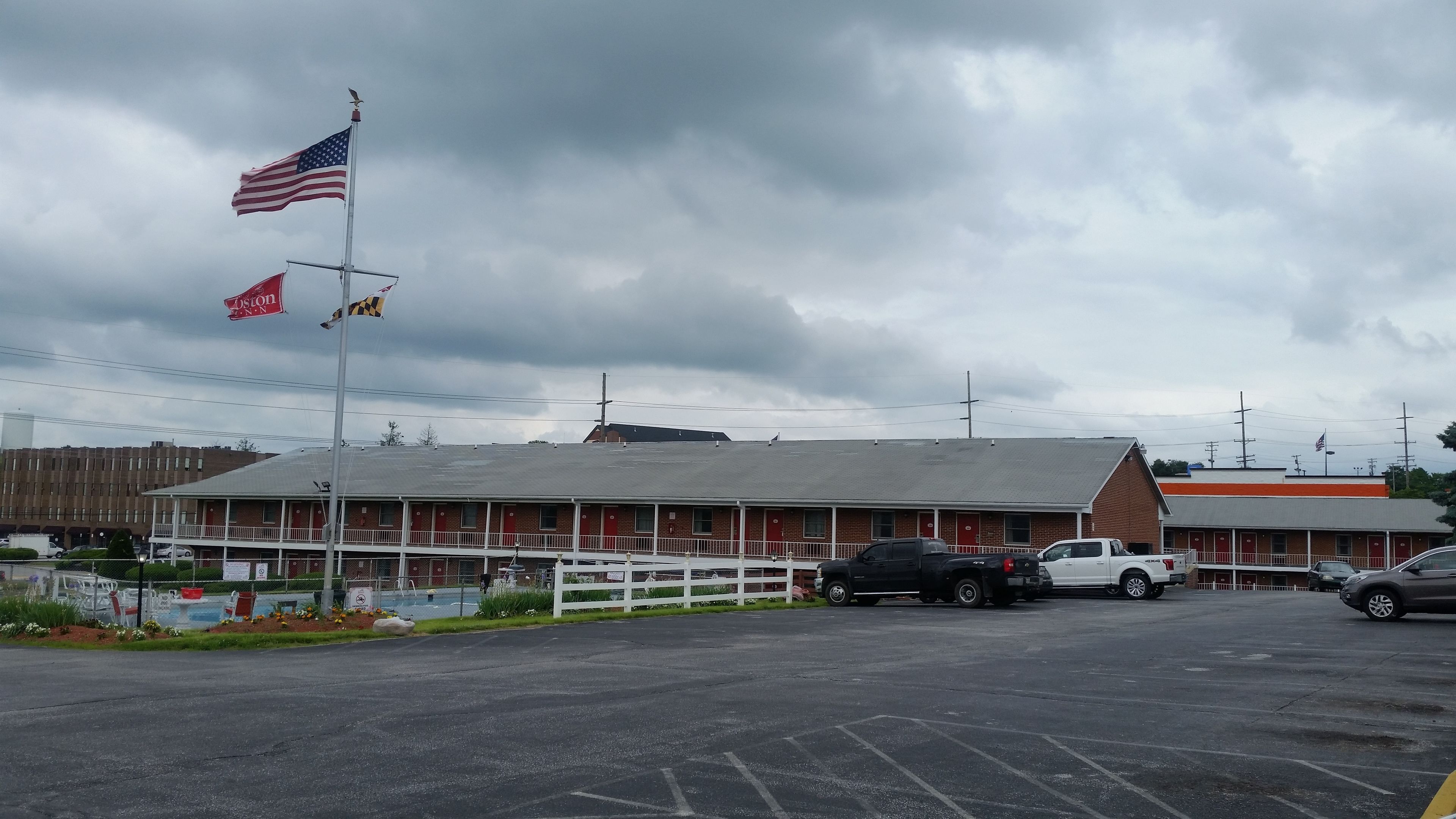 A motel with a red exterior and a white fence in front.