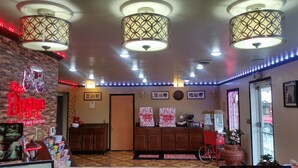 A hotel lobby with patterned ceiling lights, a Boston-themed sign, wooden cabinets, and a wheelchair symbol.
