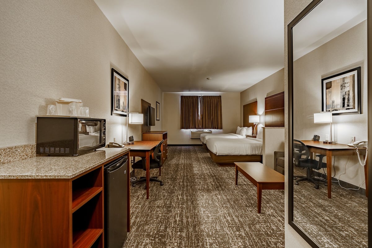 Une chambre d’hôtel avec une kitchenette, deux lits, un bureau et une salle de bain.
