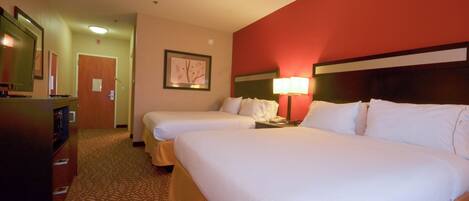 A hotel room with two beds, a desk, a lamp, and a framed picture on the wall.