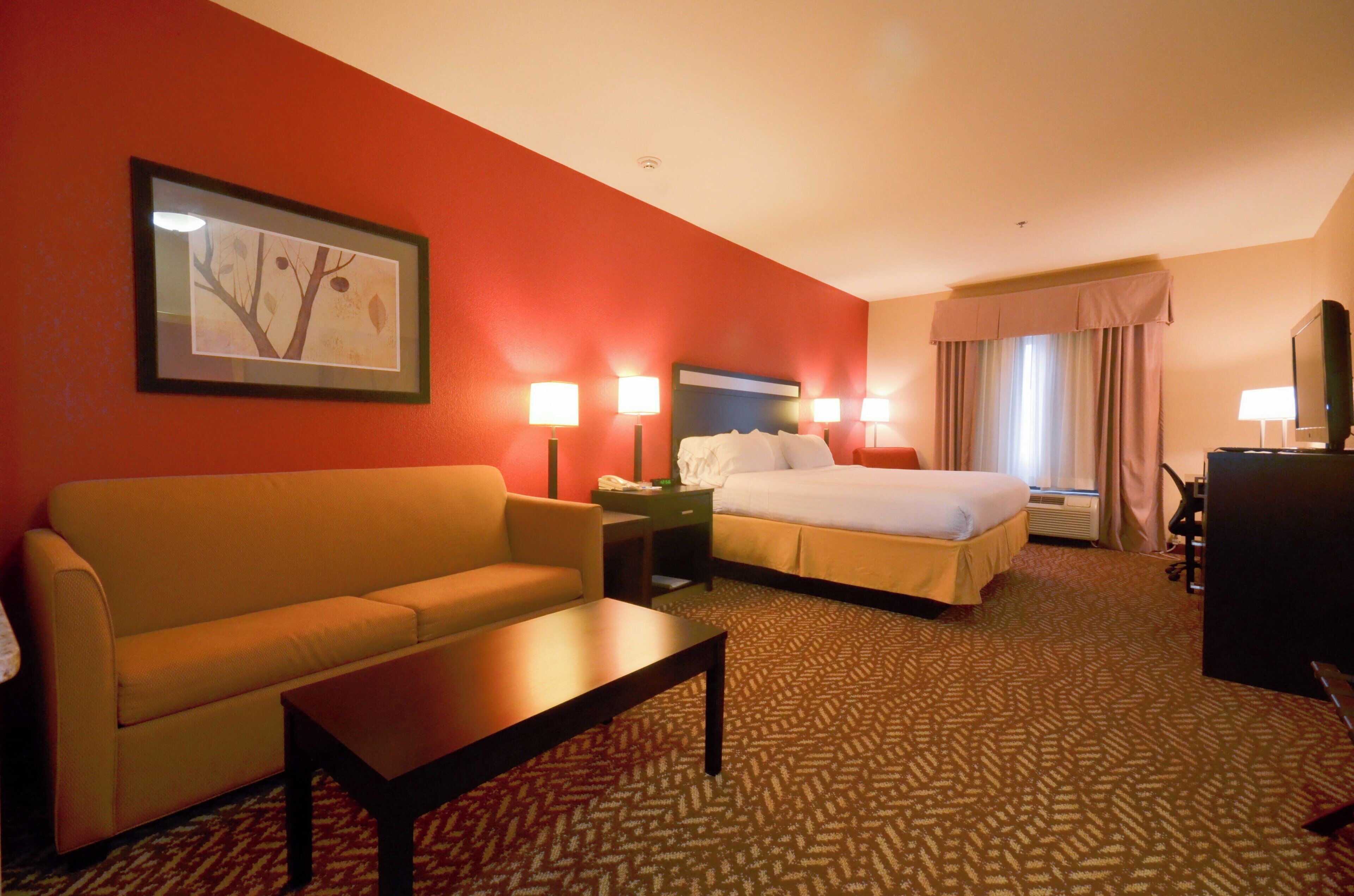 A hotel room with a bed, a sofa, a desk, and a TV.